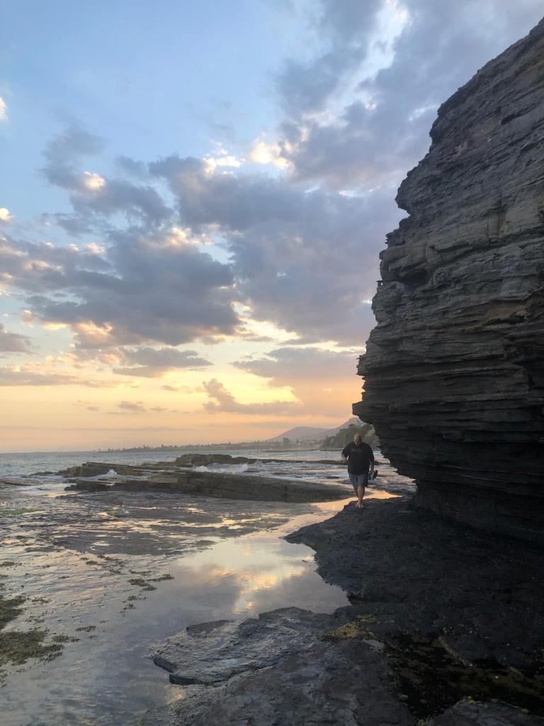 Jordan walks around the rocks near the ocean.